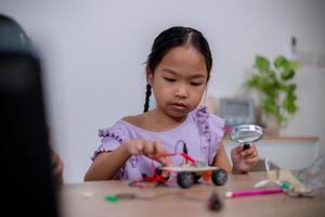 Asian students learn at home by coding robot cars and electronic board cables in STEM, STEAM, mathematics engineering science technology computer code in robotics for kids' concepts. photo