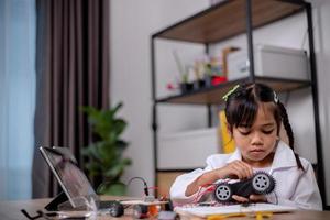 Asian students learn at home by coding robot cars and electronic board cables in STEM, STEAM, mathematics engineering science technology computer code in robotics for kids' concepts. photo
