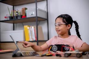 Asian students learn at home by coding robot cars and electronic board cables in STEM, STEAM, mathematics engineering science technology computer code in robotics for kids' concepts. photo
