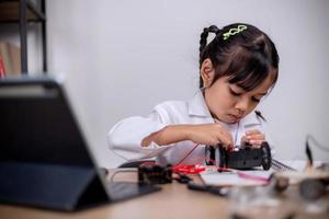 Asian students learn at home by coding robot cars and electronic board cables in STEM, STEAM, mathematics engineering science technology computer code in robotics for kids' concepts. photo