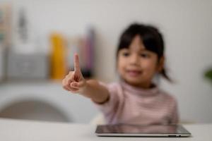 educación, escuela y concepto de pantalla imaginaria - niña asiática apuntando al aire o pantalla imaginaria foto