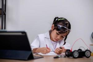 los estudiantes asiáticos aprenden en casa codificando automóviles robot y cables de placas electrónicas en tallo, vapor, ingeniería matemática, ciencia, tecnología, código informático en robótica para conceptos infantiles. foto