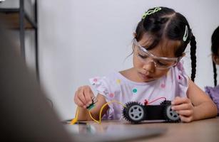 los estudiantes asiáticos aprenden en casa codificando automóviles robot y cables de placas electrónicas en tallo, vapor, ingeniería matemática, ciencia, tecnología, código informático en robótica para conceptos infantiles. foto