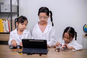 los estudiantes asiáticos aprenden en casa codificando automóviles robot y cables de placas electrónicas en tallo, vapor, ingeniería matemática, ciencia, tecnología, código informático en robótica para conceptos infantiles. foto