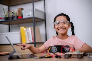 Asian students learn at home by coding robot cars and electronic board cables in STEM, STEAM, mathematics engineering science technology computer code in robotics for kids' concepts. photo