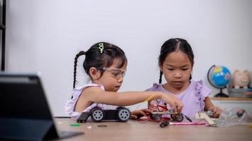 Asian students learn at home by coding robot cars and electronic board cables in STEM, STEAM, mathematics engineering science technology computer code in robotics for kids' concepts. photo