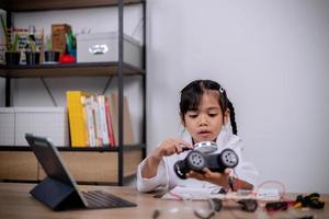 Asian students learn at home by coding robot cars and electronic board cables in STEM, STEAM, mathematics engineering science technology computer code in robotics for kids' concepts. photo