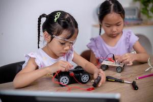 Asian students learn at home by coding robot cars and electronic board cables in STEM, STEAM, mathematics engineering science technology computer code in robotics for kids' concepts. photo