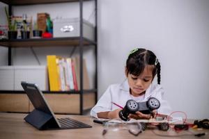 Asian students learn at home by coding robot cars and electronic board cables in STEM, STEAM, mathematics engineering science technology computer code in robotics for kids' concepts. photo