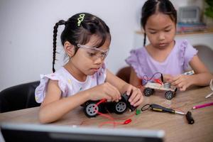 los estudiantes asiáticos aprenden en casa codificando automóviles robot y cables de placas electrónicas en tallo, vapor, ingeniería matemática, ciencia, tecnología, código informático en robótica para conceptos infantiles. foto