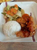 Flour fried chicken doused with special spices and served with vegetables on a white plate photo