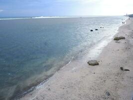 View of the shoreline from above, white waves, beach sand, clear water and rocks. Panoramic view. Beautiful beaches photo