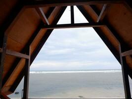 Beautiful view of the beach from inside a wooden house or gazebo photo