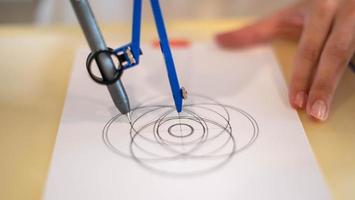 Female hand using a measure circle preparing to draw and sketch on the empty white paper. photo