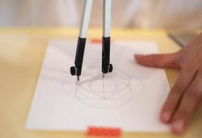 Female hand using a measure circle preparing to draw and sketch on the empty white paper. photo