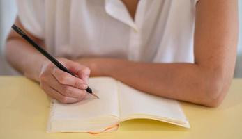 mano femenina tomando nota con lápiz y cuaderno vacío en su habitación. foto