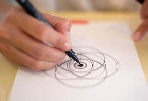 Female hand using a black magic pen preparing to draw and sketch the mandala concept on the empty white paper. photo