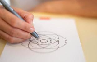 Female hand using a black magic pen preparing to draw and sketch the mandala concept on the empty white paper. photo