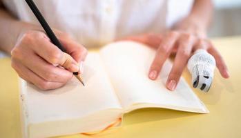 Female hand making note with pencil and empty notebook in their room. photo