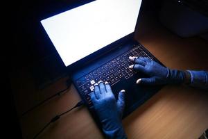 Mano de hacker robando datos de la computadora portátil de arriba hacia abajo foto