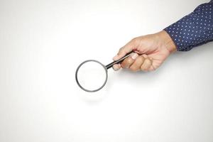hand holding magnifying glass against white photo