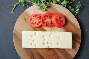 vista superior de queso y tomate en una tabla de cortar en la mesa foto