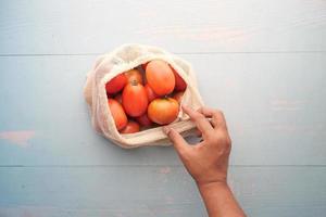 fresh tomato in a reusable shopping bag on table photo