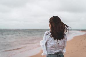 Young woman feeling lonely and sad looking at the sea on a cloudy day photo