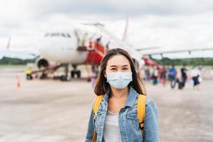 mujer joven con mascarilla en el aeropuerto, nuevo concepto de estilo de vida normal foto