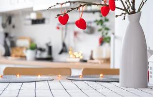 Valentine decor on table of white kitchen in cozy home. Copy space. Gift for valentines day, family love nest. A vase with a bouquet of hearts in a modern interior. photo