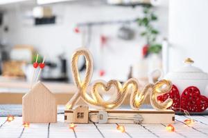 Key to house of cozy home with Valentine decor on table of kitchen. Gift for valentines day, family love nest. Building, design, project, moving to new house, mortgage, rent and purchase real estate photo