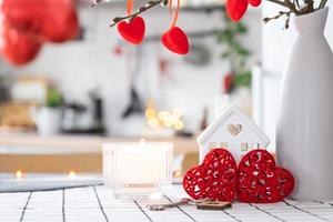 Key to house of cozy home with Valentine decor on table of kitchen. Gift for valentines day, family love nest. Building, design, project, moving to new house, mortgage, rent and purchase real estate photo