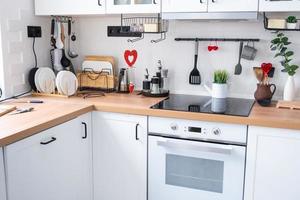 The interior of the kitchen in the house is decorated with red hearts for Valentine's Day. Decor on the table, stove, utensils, festive mood in a family nest photo