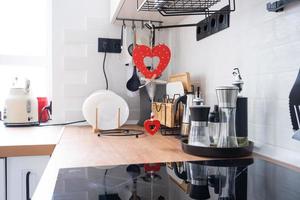 el interior de la cocina de la casa está decorado con corazones rojos para el día de san valentín. decoración en la mesa, estufa, utensilios, ambiente festivo en un nido familiar foto