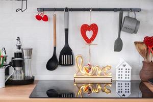 el interior de la cocina de la casa está decorado con corazones rojos para el día de san valentín. decoración en la mesa, estufa, utensilios, ambiente festivo en un nido familiar foto