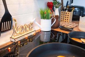 el interior de la cocina de la casa está decorado con corazones rojos para el día de san valentín. decoración en la mesa, estufa, utensilios, ambiente festivo en un nido familiar foto