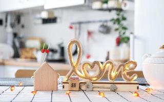 Key to house of cozy home with Valentine decor on table of kitchen. Gift for valentines day, family love nest. Building, design, project, moving to new house, mortgage, rent and purchase real estate photo