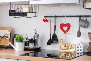 el interior de la cocina de la casa está decorado con corazones rojos para el día de san valentín. decoración en la mesa, estufa, utensilios, ambiente festivo en un nido familiar foto