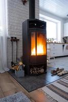 Black stove, fireplace in interior of house in loft style. Alternative eco-friendly heating, warm cozy room at home, burning wood photo