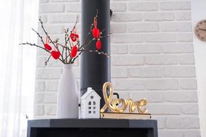 Valentine decor near fireplace stove with fire and firewood. Cozy home hearth in interior with potted plans, valentines day in family love nest. photo