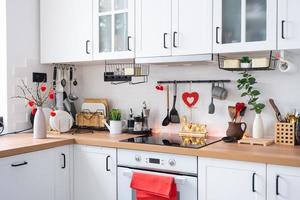 el interior de la cocina de la casa está decorado con corazones rojos para el día de san valentín. decoración en la mesa, estufa, utensilios, ambiente festivo en un nido familiar foto