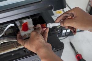 The technician is repairing the printer. By sucking out the paint to chase bubbles. photo