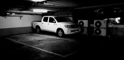 Bangkok, Thailand - January 30, 2023 White car on parking lot in building with neon light in black and white style. Vehicle, Transportation and Art concept photo