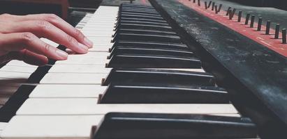 cierre la mano de las personas que tocan el piano o presione el teclado de tono elegido en estilo de color vintage. concepto de objeto, música e instrumento foto