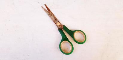 Old green rusty scissor putting or isolated on white board background. Vintage or Single object concept photo