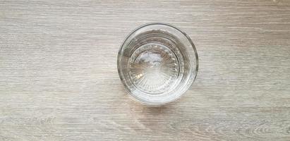 Top view or Flat lay Glass of cold water putting on light brown or gray wooden table for background with copy space. Refreshment, Drink, Object, Clearly and Shinning concept photo