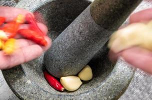 Pepper and garlic pounded in a stone mortar photo