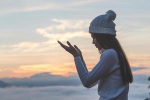 Young christian woman  hands open palm up worship and praying to god  at sunrise, Christian Religion concept background. photo