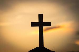 Silhouette of crucifix cross at sunset time with holy and light background. photo