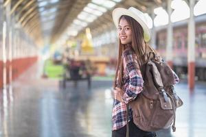 woman with suitcase waiting for her train on platform of railway station, summer travel. photo